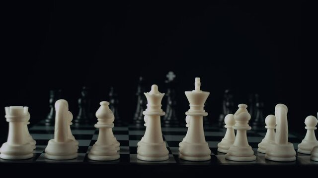Game of chess. Waiting for the start. Male hand puts a white chess piece pawn on the chessboard on black background. The concept of business strategy, startup, success. Depth of field. Red camera, 4K