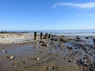 A view of the beach and the sea and numerous remnants of concrete and metal - A beach with a mess