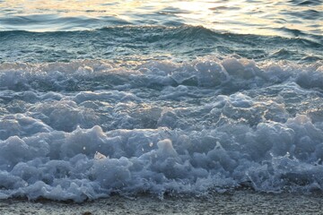 Blue sea waves with bubbles and foam on the beach