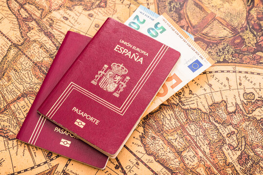 Spanish passport with euro bills inside, on a world map for travelers.