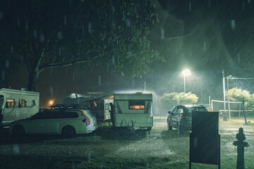 Rainy evening in the campsite. Rain drops are silverly sparkling in the white lights of campsite...
