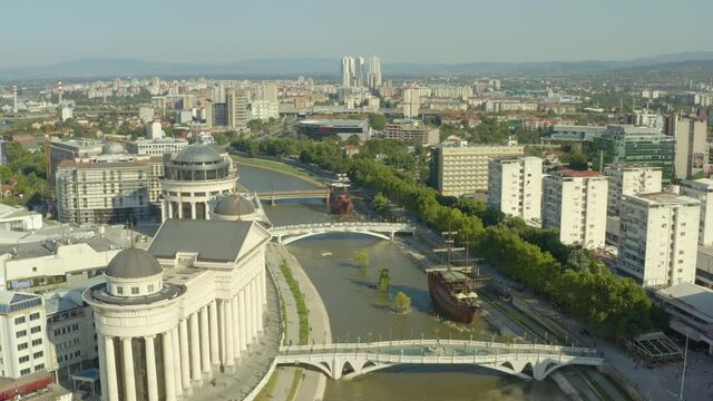 Aerial view Skopje Macedonia. A drone flew over the river Vardar with ships and bridges over it in the city center with houses, skyscrapers, streets, mountains in the background.