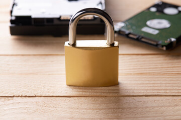 hardware data protection technology concept. stack hard drive discs and golden padlock over wooden background. studio shot. privacy data conceptual