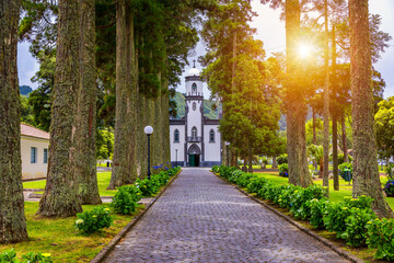 Church of Sao Nicolau (Saint Nicolas) with an alley of tall trees and hydrangea flowers in Sete cidades on Sao Miguel island, Azores, Portugal. Parish Church of St. Nicholas, Sete Cidades, Azores.
