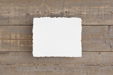 Horizontal 8x10 deckle edge, cold pressed watercolour paper mockup. Flat lay on an old wooden, brown desk.
