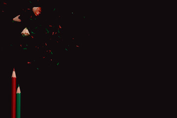 Colorful pencils with sharpening waste on dark background, side border from top view. Empty space for text.