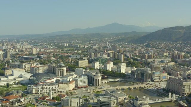Drone video of the parliament building standing on the river bank with bridges surrounded by old houses in the city center. Arial shot Skopje Macedonia.