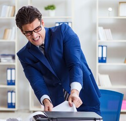 Businessman angry at copying machine jamming papers