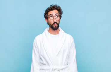 young bearded man wearing a bath robe with a worried, confused, clueless expression, looking up to...