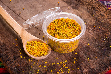 Polen de abeja natural artesanal orgánico con cucharon de madera rústica en pote de plástico...