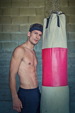 A handsome young man practicing boxing on a punching bag