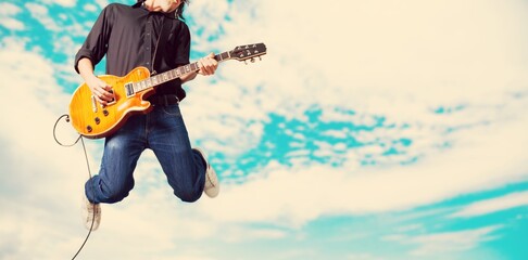 Male guitarist playing music and jump