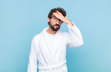 young bearded man wearing a bath robe panicking over a forgotten deadline, feeling stressed, having...