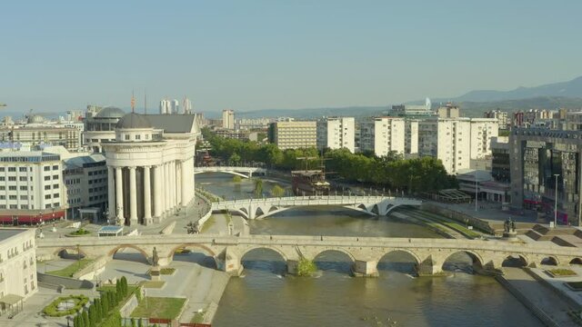 Aerial view Skopje Macedonia. A drone flew over the river Vardar with ships and bridges over it in the city center with houses, skyscrapers, streets, mountains in the background.