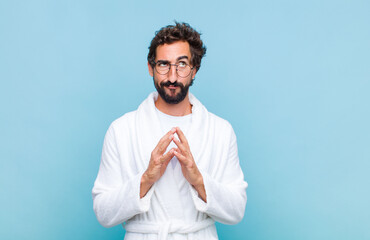 young bearded man wearing a bath robe scheming and conspiring, thinking devious tricks and cheats,...