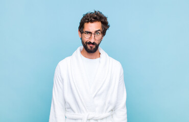 young bearded man wearing a bath robe feeling confused and doubtful, wondering or trying to choose...