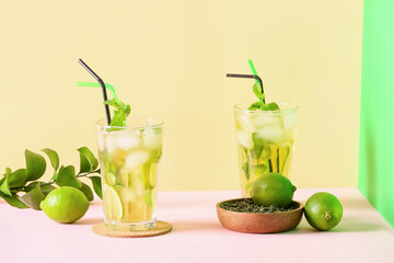 Glasses of tasty cold ice tea on color background
