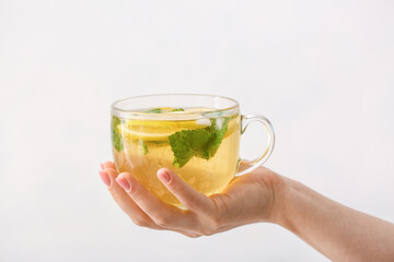 Female hand with cup of tasty cold ice tea on white background