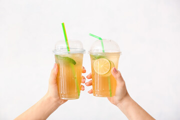 Female hands with cups of tasty cold ice tea on white background
