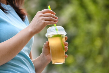 Woman drinking tasty cold ice tea outdoors, closeup