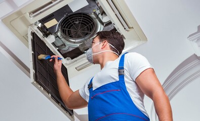 Worker repairing ceiling air conditioning unit