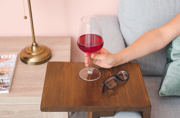 Woman with glass of wine resting on sofa at home