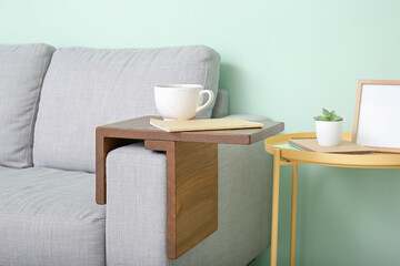 Cup of tea with notebook on armrest table in room