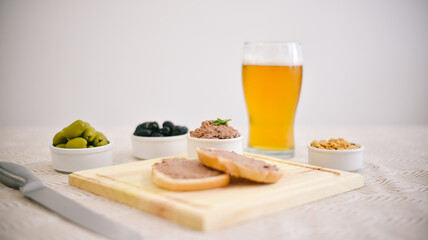 Tostadas con leberwurst acompañado por aceitunas, maní y cerveza