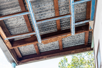 A decayed wood structure under the zinc roof of a house.