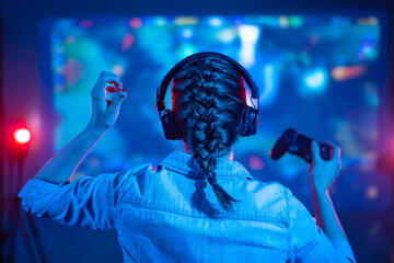 Gamer girl playing in front of a big TV, screen in games, e-sports, gamer, streamer, streaming games