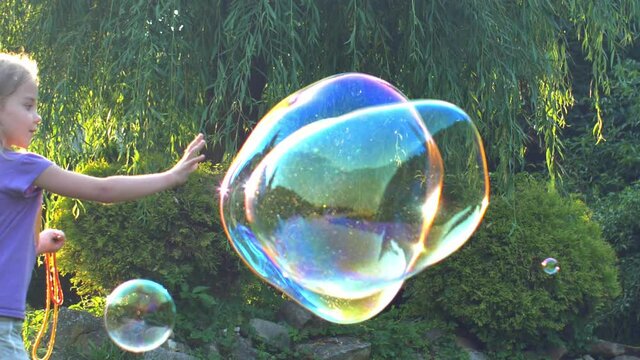 Young Girl Playing with Giant Soap Bubbles at Sunset Backlit View 