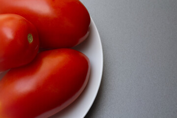 Three ripe tomatoes on a white plate