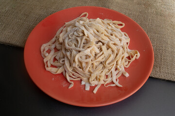 Raw homemade pasta floured on orange platen