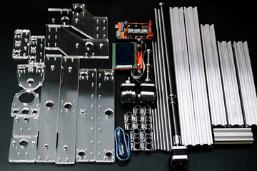 a set of parts for a laser machine on a black background, silver backlight, flat lay arduino board for controlling the machine and v slot aluminum profile lies .