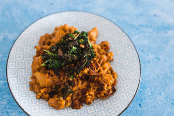 plant-based food, vegan butter beans cannellini and cauliflower stew in pumpkin sauce with kale topping