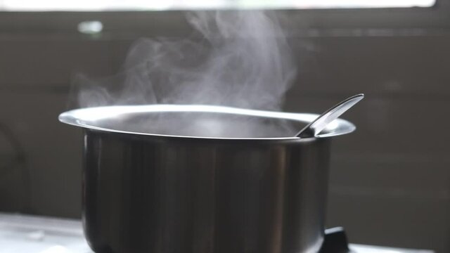 Milk is being boiled in a metal pot on the gas oven. Indian household and kitchen