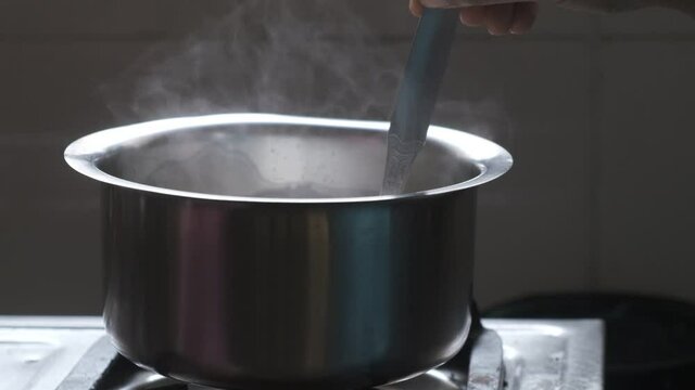 Milk is being boiled in a metal pot on the gas oven. Indian household and kitchen