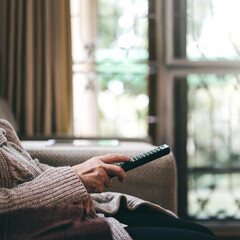 Asian elderly hand holding remote television and watching movie.