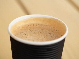 Full paper glass of coffee. Foam texture. Close-up top-down view.