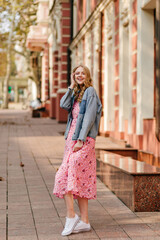 vertical full-length photo of a romantic blond girl touching her hair and looking into the camera