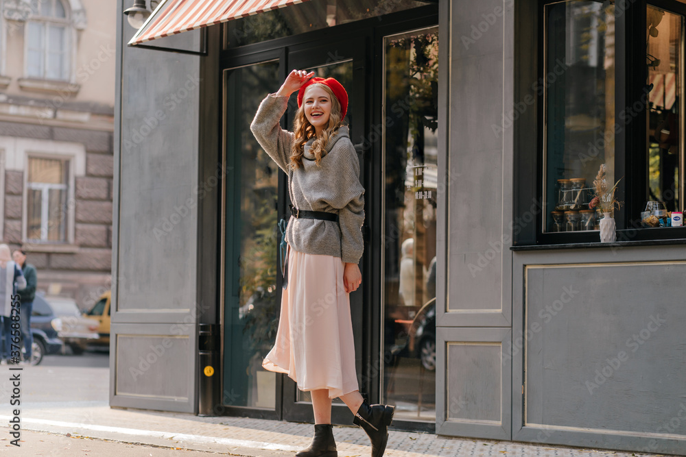 Wall mural Full-length photo, pretty model in stylish outfit, sincerely smiles at the camera and waves her hand