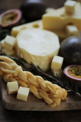 Cheese platter.Soft and hard cheeses set, passionfruit cut, rosemary on dark and light boards on a wooden table.Rustic cheeses.Pieces of cheese close-up.Delicious cheese menu