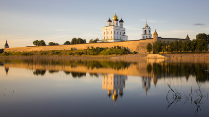 Fototapeta na wymiar Pskov Kremlin and Troitsky Cathedral at sunrize reflected in still river water