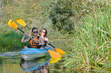 Family kayaking, mother and daughter paddling in kayak on river canoe tour having fun, active weekend and vacation with children, fitness concept
