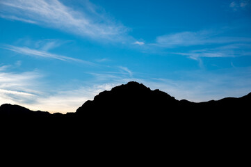 Silhouette of a mountain range against a vivid blue sky