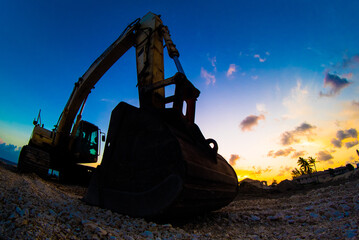 A shot of a large mechanical digger against the setting sun in the Caribbean