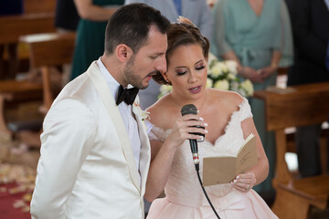 Bride and groom with white tuxedo speaking into microphone at wedding ceremony