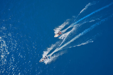 Top view of two boats sailing at high speed. Aerial view of boats in motion on blue water.