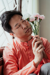 Asian Gay is absent-minded while holding flowers.