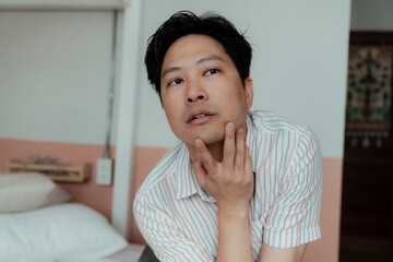 Fototapeta na wymiar Asian gay in stripped shirt touch his chin with sexy posture.
